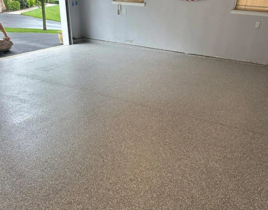 Tan flake epoxy garage floor with the door open on a bright day