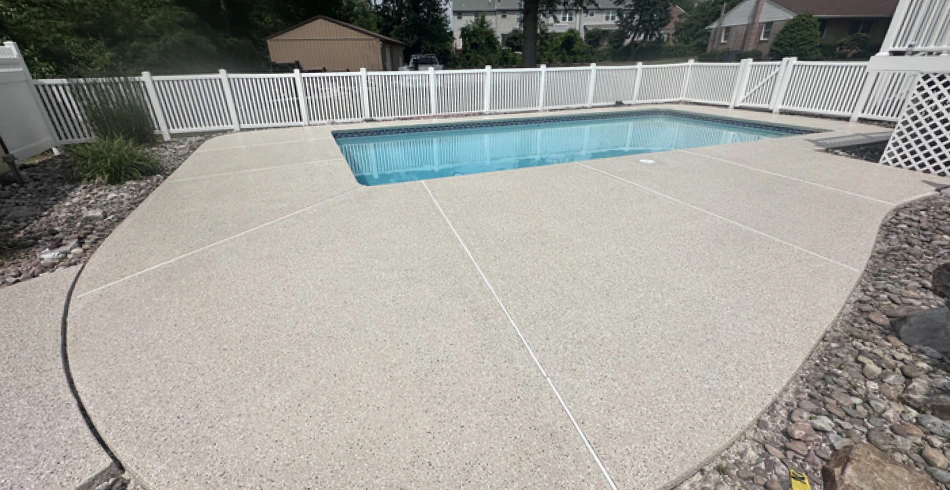 Tan flake epoxy pool deck surrounding an in ground pool at a Pennsylvania home